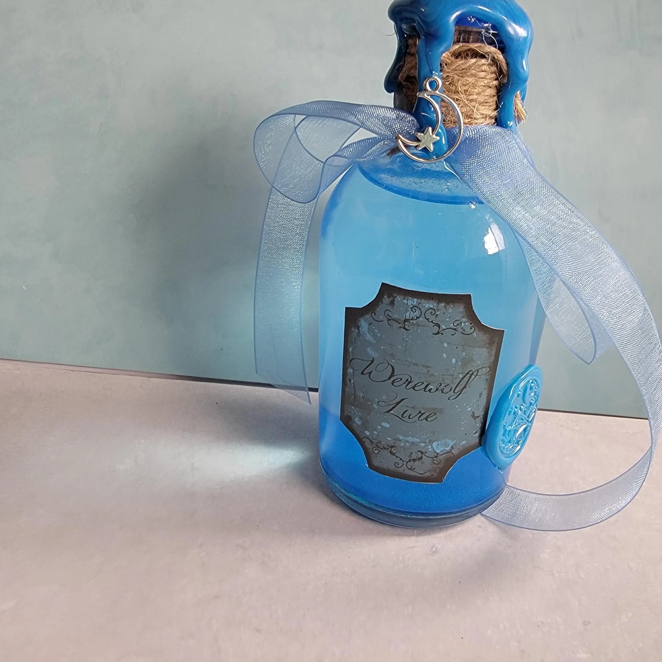 Blue bottle with decorative label and ribbon on a neutral background