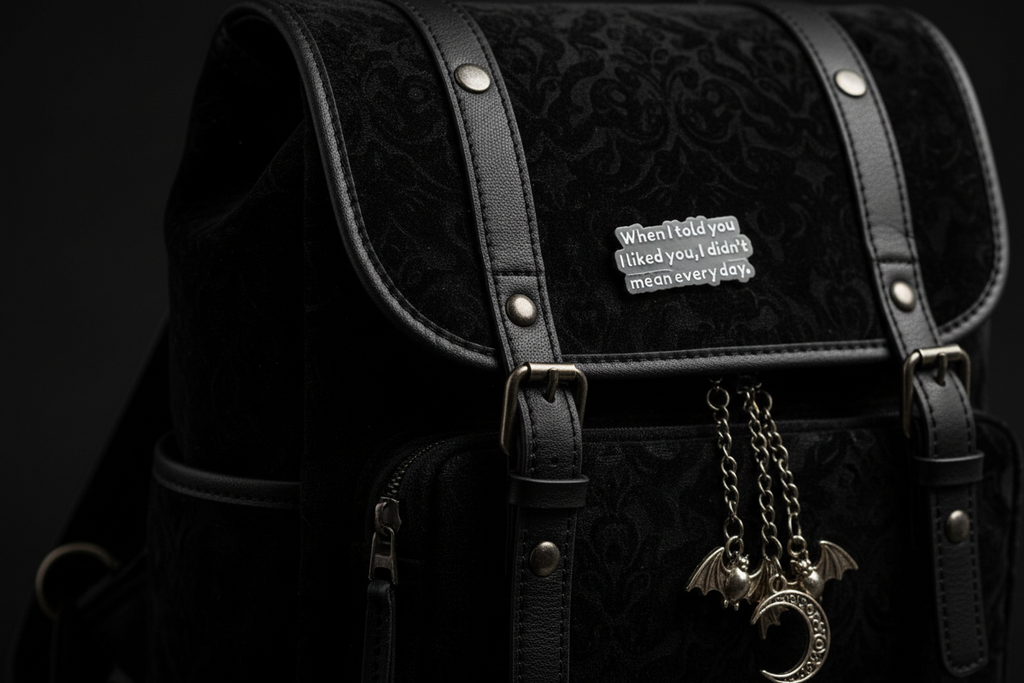 black enamel pin with white text and a sarcastic saying on a black bag background