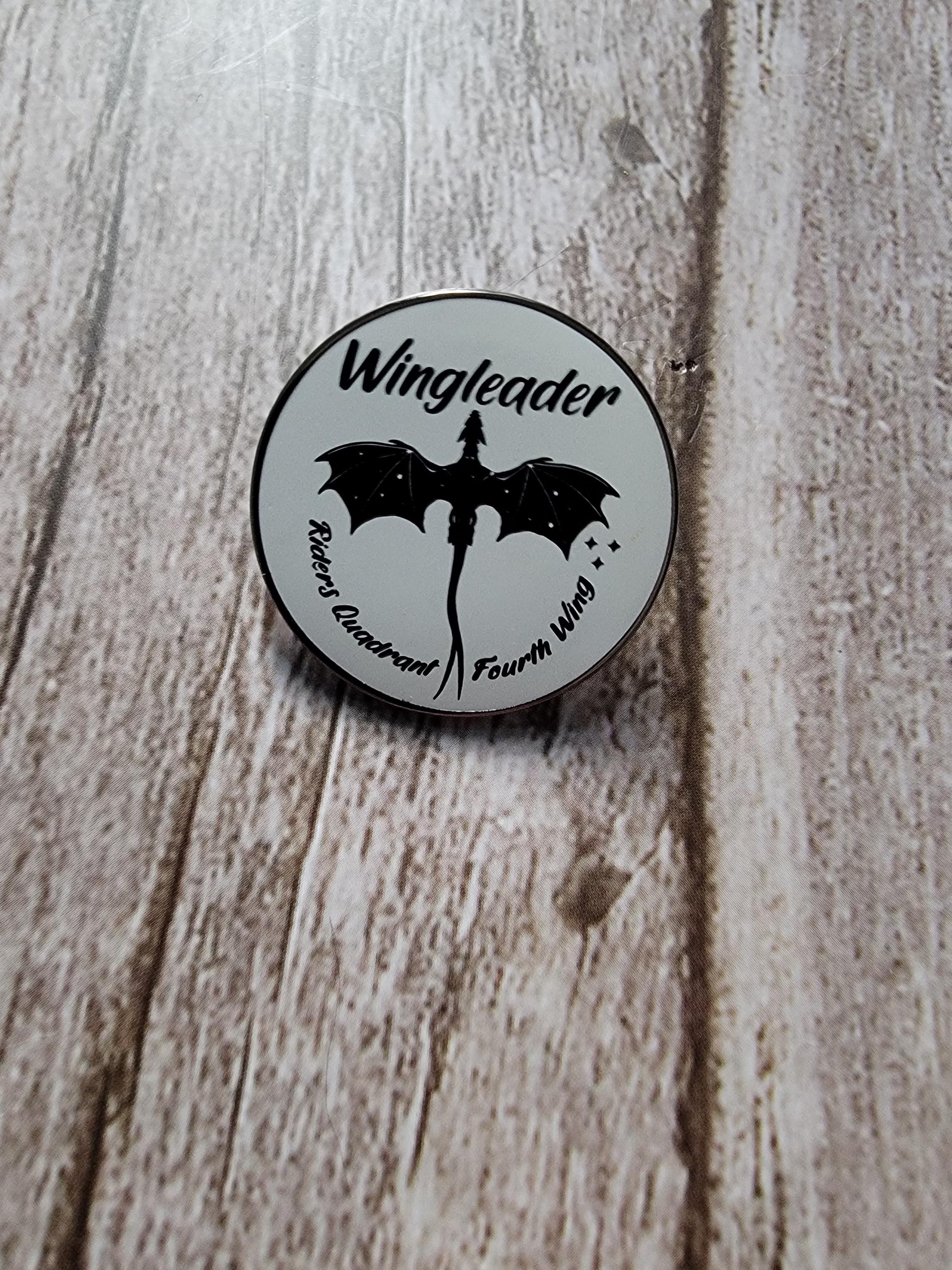 Round badge with 'Wingleader' text and bat design on a wooden surface