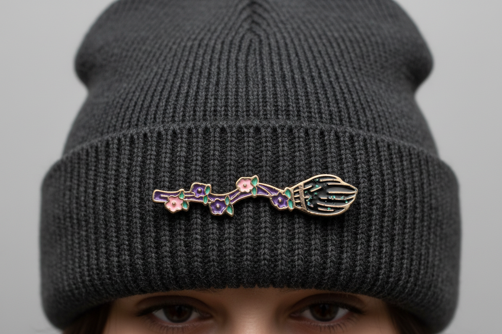 witch broom enamel pin worn on beanie hat alternative enamel pin for casual outfits and street wear